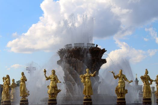 Stunning fountain with golden statues under a blue sky at VDNKh, showcasing artistic craftsmanship.